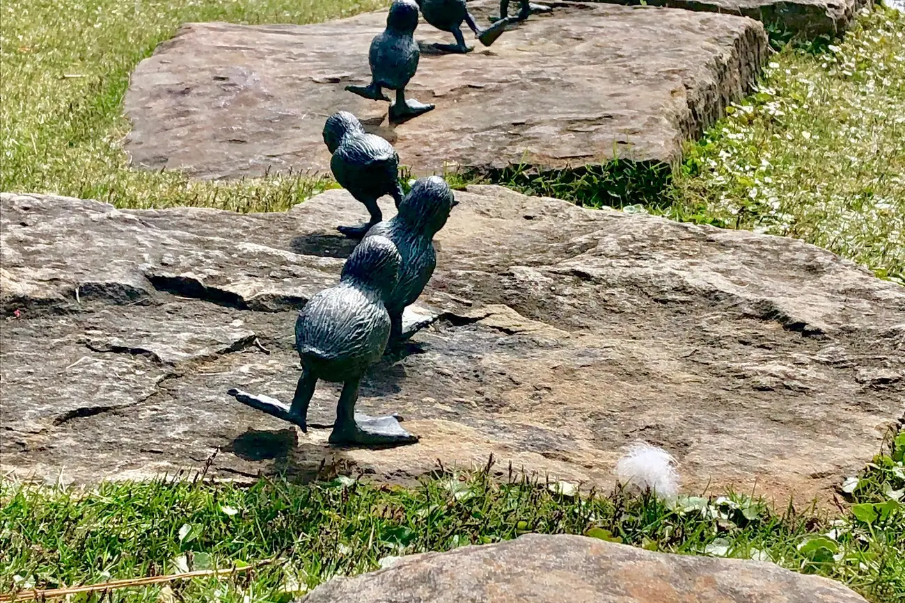 Small bronze birds from Frank Fleming's sculpture "Come Along" cross the stones at Aldridge Gardens in Hoover.